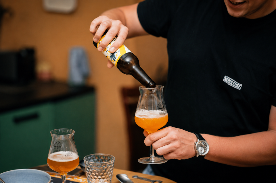 Un homme qui verse une bière dans un verre.